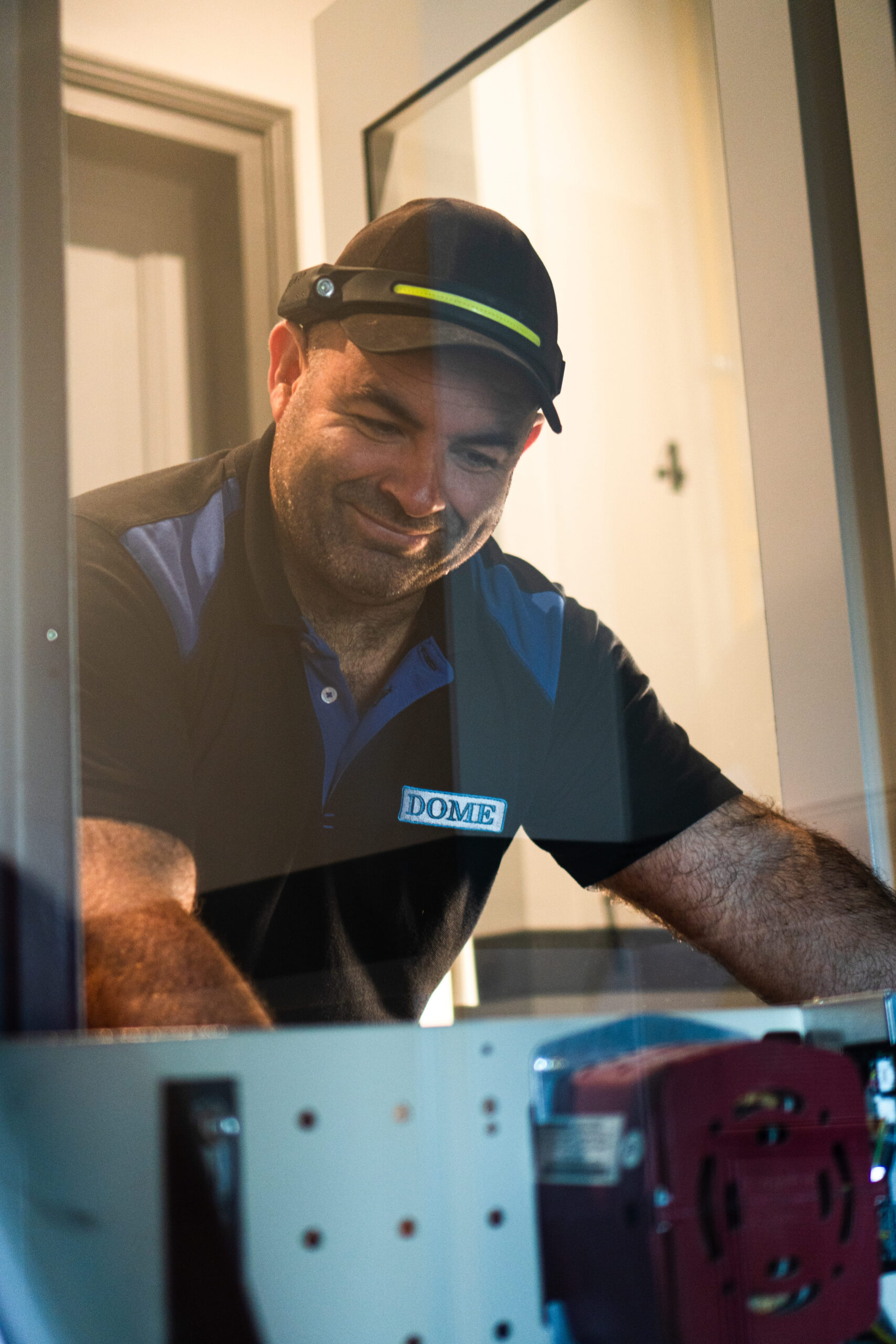 Photo d'un technicien heureux de chez DOME entrain de s'occuper de la maintenance d'un ascenseur dans l'Essonne.